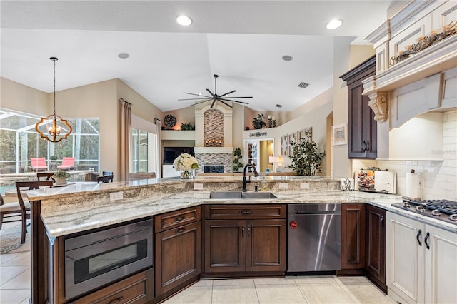 kitchen featuring a tile fireplace, sink, hanging light fixtures, dark brown cabinetry, and stainless steel appliances