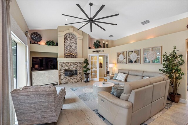 living room with a tiled fireplace and high vaulted ceiling