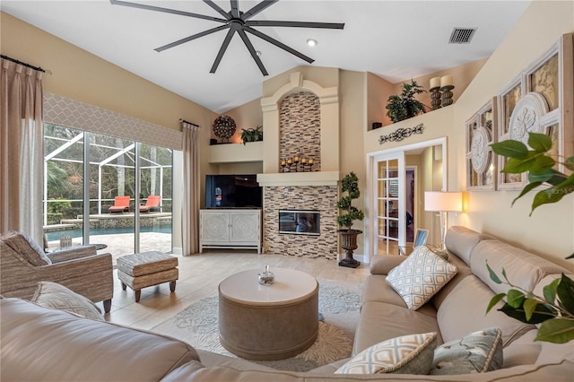 living room with high vaulted ceiling, a tile fireplace, and ceiling fan