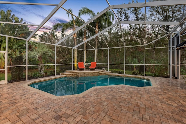 pool at dusk with a patio and glass enclosure