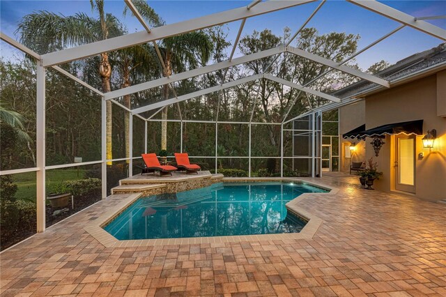 pool at dusk featuring a lanai and a patio area