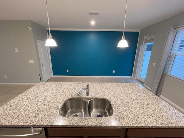 kitchen featuring light stone countertops, pendant lighting, light tile patterned flooring, and sink