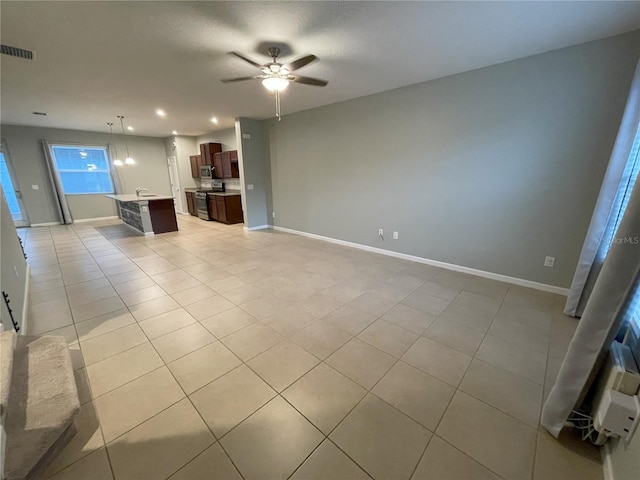 unfurnished living room featuring light tile patterned floors, ceiling fan, and sink