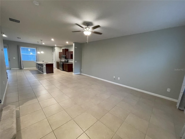 unfurnished living room with ceiling fan, light tile patterned floors, and sink