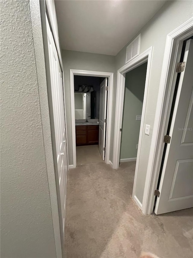 hall featuring light carpet and sink