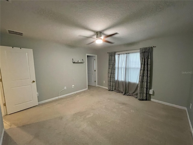 carpeted spare room featuring ceiling fan and a textured ceiling