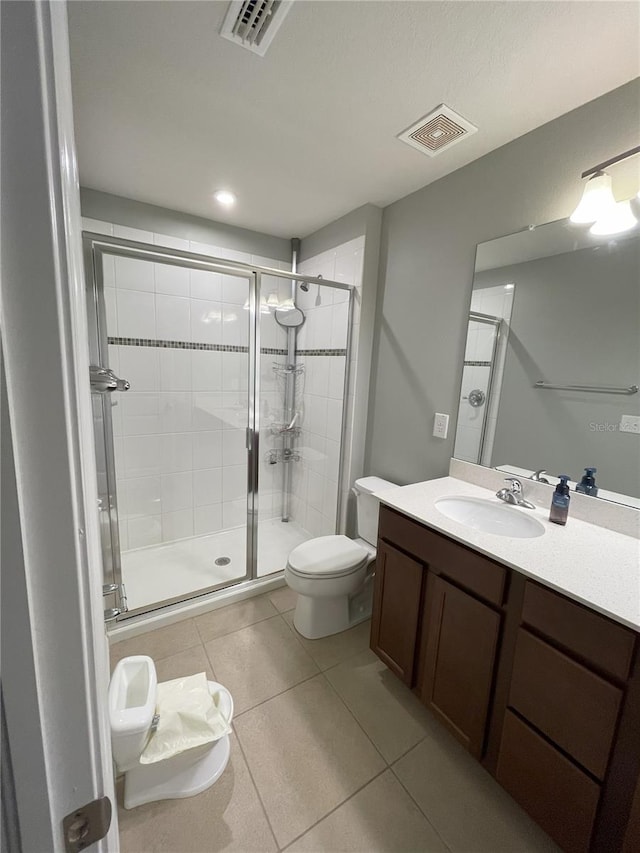 bathroom featuring tile patterned flooring, vanity, toilet, and a shower with door