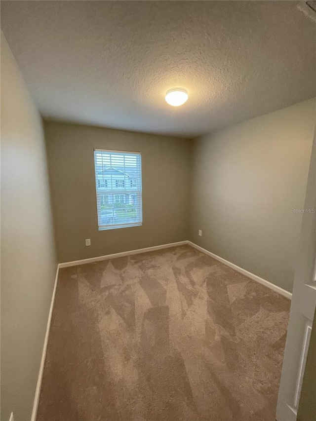 carpeted empty room featuring a textured ceiling