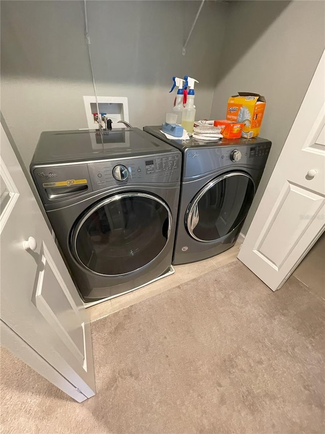 clothes washing area featuring light carpet and independent washer and dryer