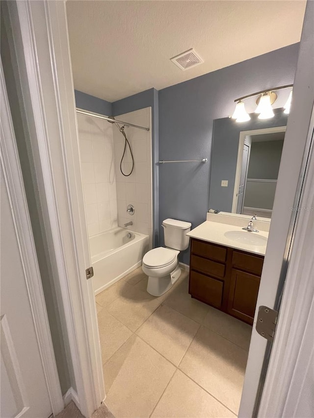 full bathroom featuring vanity, tile patterned flooring, tiled shower / bath combo, toilet, and a textured ceiling