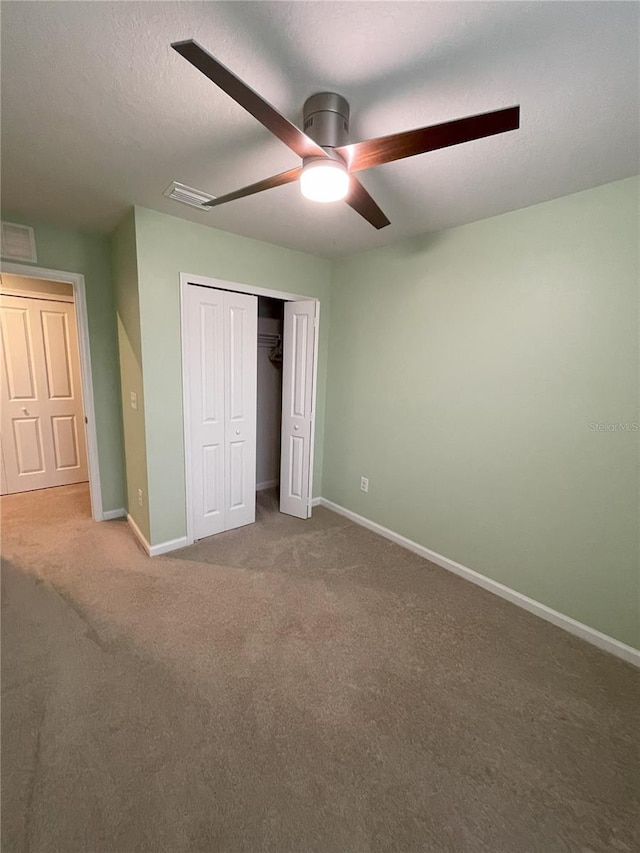 unfurnished bedroom with carpet flooring, ceiling fan, a textured ceiling, and a closet