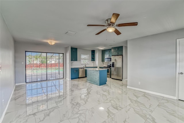 kitchen featuring appliances with stainless steel finishes, a center island, blue cabinets, and ceiling fan