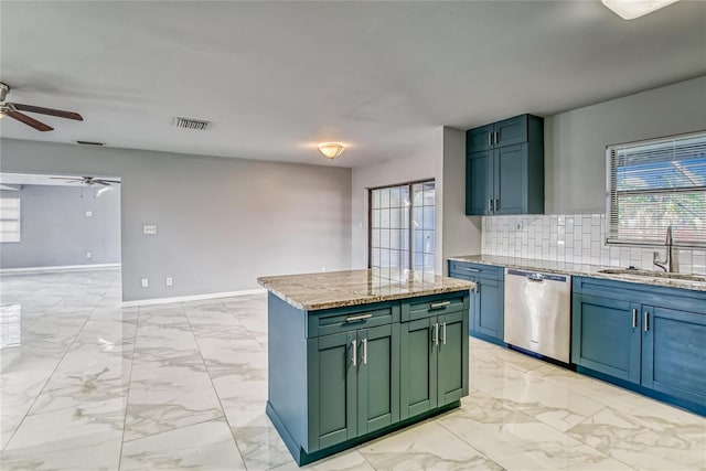 kitchen featuring backsplash, light stone counters, stainless steel dishwasher, sink, and a center island