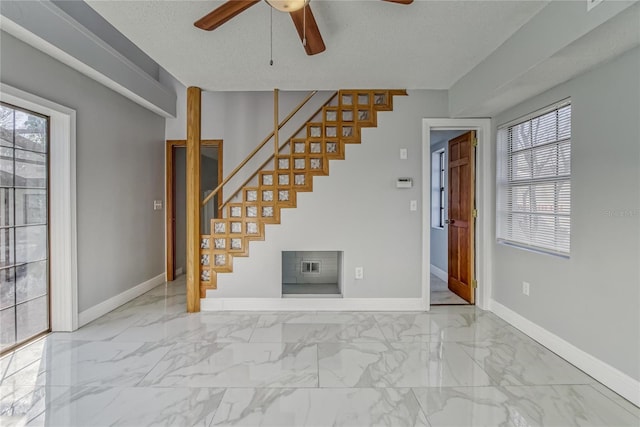 interior space with a wealth of natural light, ceiling fan, and a textured ceiling