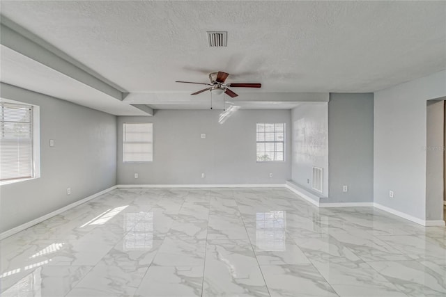 empty room with ceiling fan and a textured ceiling