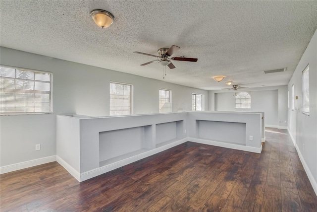 empty room featuring a textured ceiling, dark hardwood / wood-style flooring, and a wealth of natural light