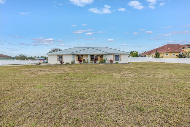 single story home with metal roof, a front yard, and fence