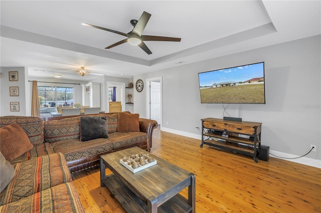 living room featuring ceiling fan, hardwood / wood-style floors, and a raised ceiling