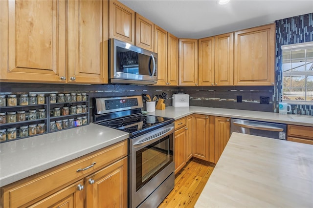 kitchen with decorative backsplash, appliances with stainless steel finishes, butcher block counters, and light hardwood / wood-style flooring