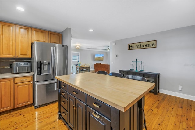 kitchen with stainless steel fridge, wooden counters, ceiling fan, a kitchen island, and light hardwood / wood-style flooring