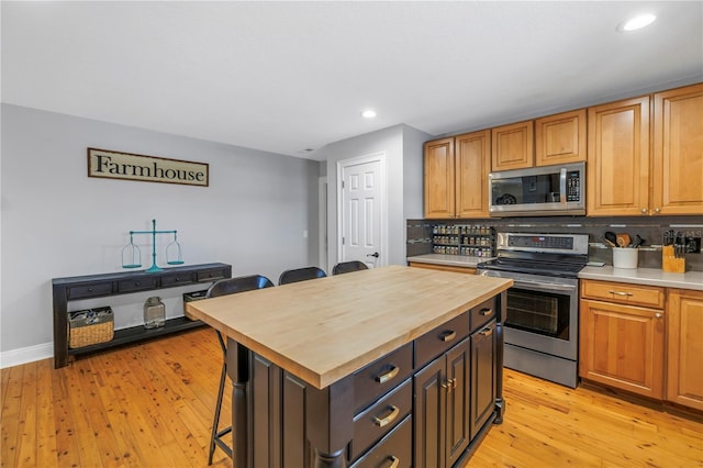 kitchen featuring appliances with stainless steel finishes, butcher block counters, tasteful backsplash, and a kitchen island