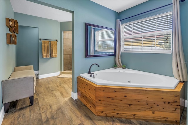 bathroom with a tub to relax in and wood-type flooring