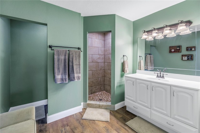 bathroom with a tile shower, hardwood / wood-style flooring, and vanity