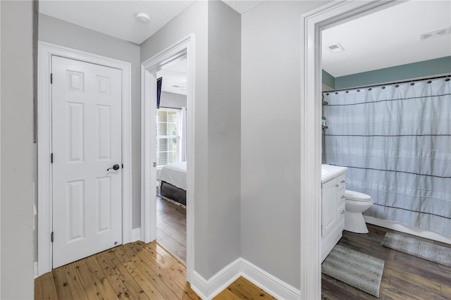 bathroom featuring toilet, walk in shower, hardwood / wood-style flooring, and vanity