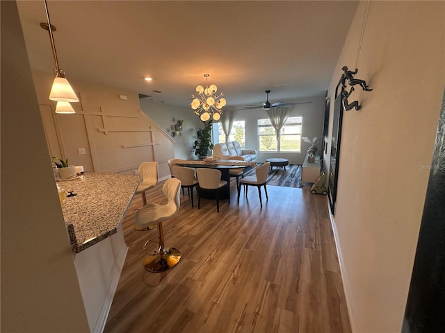 dining area featuring hardwood / wood-style floors and ceiling fan with notable chandelier