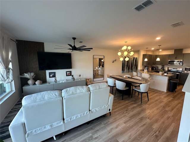 living room with wood-type flooring and ceiling fan with notable chandelier