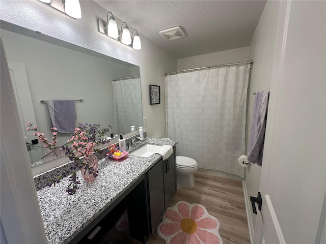 bathroom with vanity, a textured ceiling, hardwood / wood-style flooring, and toilet