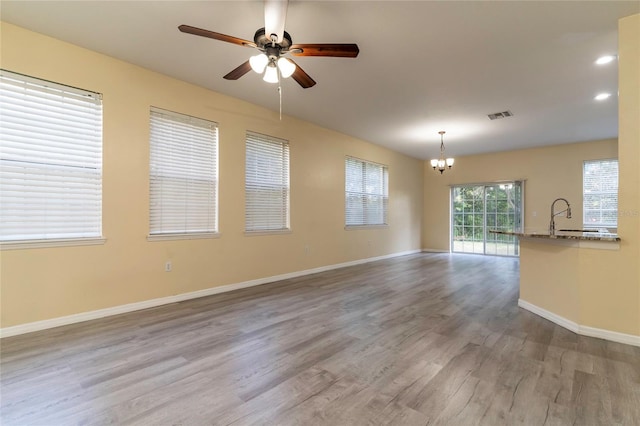 empty room featuring light hardwood / wood-style flooring, ceiling fan with notable chandelier, and sink