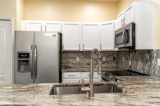 kitchen featuring white cabinets, stainless steel appliances, light stone counters, and tasteful backsplash