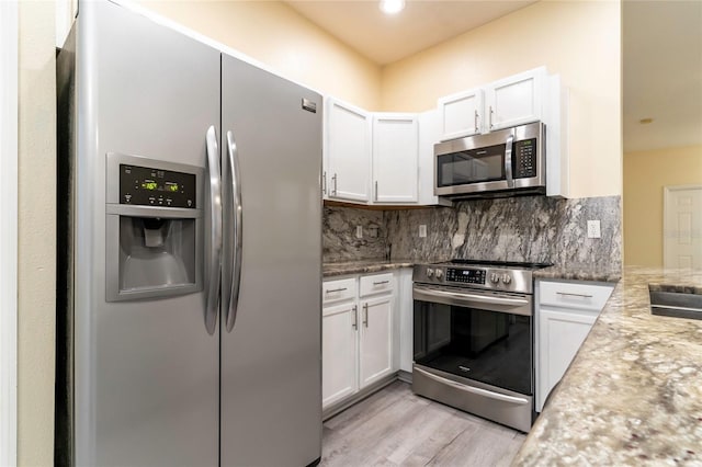 kitchen with light hardwood / wood-style flooring, light stone countertops, tasteful backsplash, white cabinetry, and stainless steel appliances