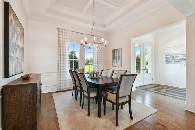 dining space with french doors, light hardwood / wood-style flooring, a notable chandelier, and crown molding