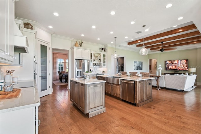 kitchen featuring light stone countertops, appliances with stainless steel finishes, sink, a center island with sink, and hanging light fixtures