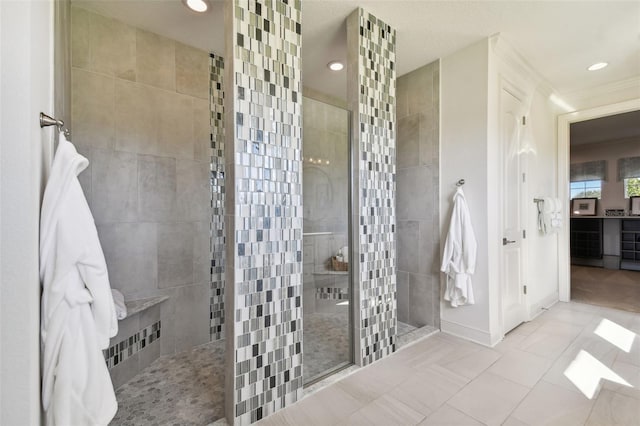 bathroom with a tile shower, tile patterned floors, and crown molding