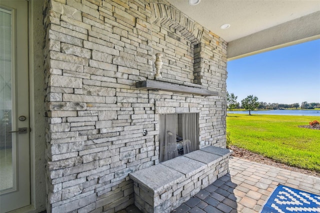 view of patio / terrace featuring an outdoor stone fireplace and a water view