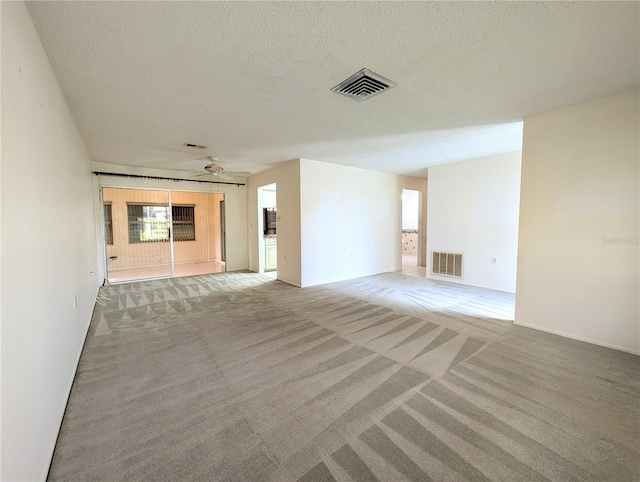 unfurnished living room featuring carpet, a textured ceiling, and ceiling fan