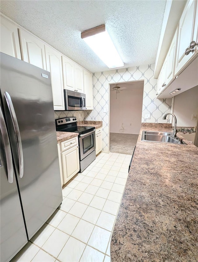 kitchen featuring a textured ceiling, stainless steel appliances, white cabinetry, and sink