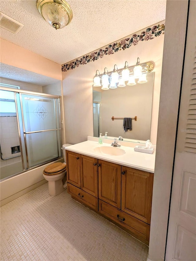 full bathroom featuring vanity, a textured ceiling, toilet, and shower / bath combination with glass door