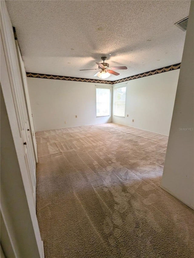 spare room featuring light carpet, a textured ceiling, and ceiling fan