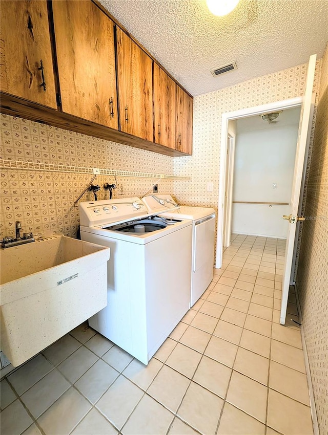 washroom featuring cabinets, sink, separate washer and dryer, a textured ceiling, and light tile patterned floors