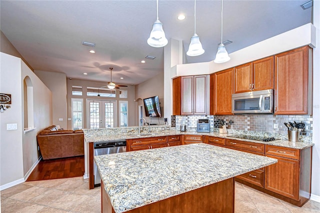 kitchen with brown cabinets, stainless steel microwave, a peninsula, decorative backsplash, and dishwasher