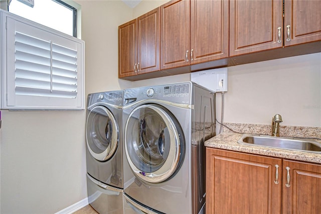 washroom featuring a sink, baseboards, cabinet space, and separate washer and dryer