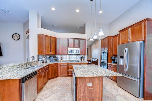 kitchen with backsplash, a kitchen island, light stone counters, appliances with stainless steel finishes, and a sink