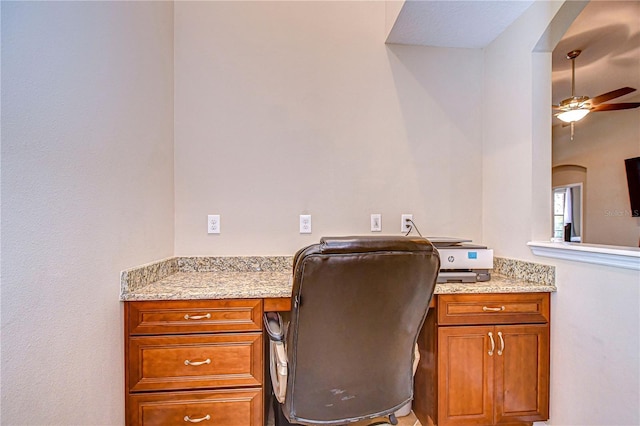 office area featuring arched walkways, built in desk, and ceiling fan