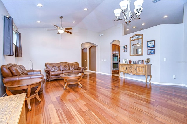 living room with light wood finished floors, baseboards, lofted ceiling, ceiling fan with notable chandelier, and arched walkways