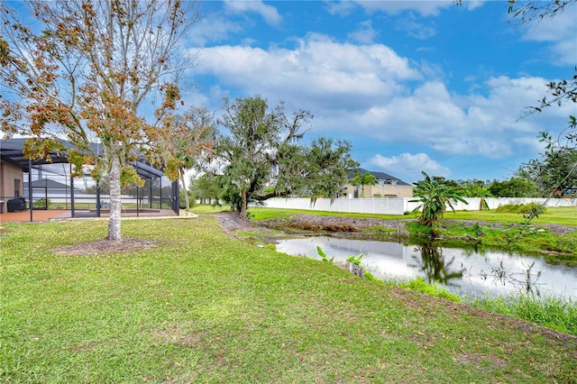 view of yard featuring glass enclosure, a water view, and fence