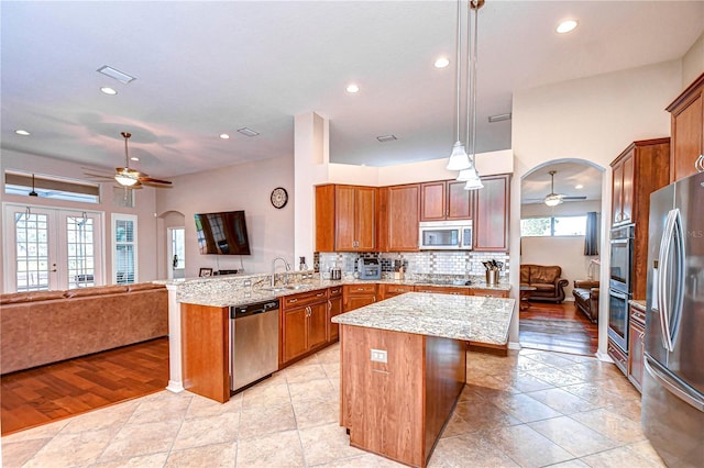 kitchen featuring stainless steel appliances, open floor plan, a peninsula, and ceiling fan